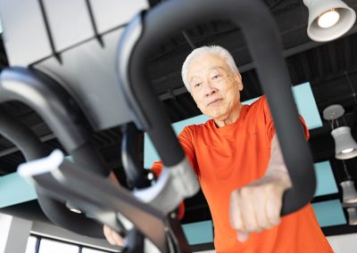 man in orange shirt on bike machine in gym