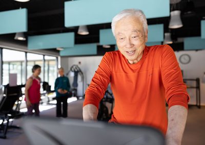 man in orange shirt on treadmill in gym