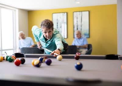 older woman in teal shirt playing pool